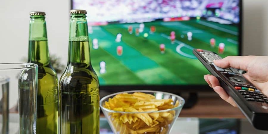 man watching tv while drinking alcohol at home