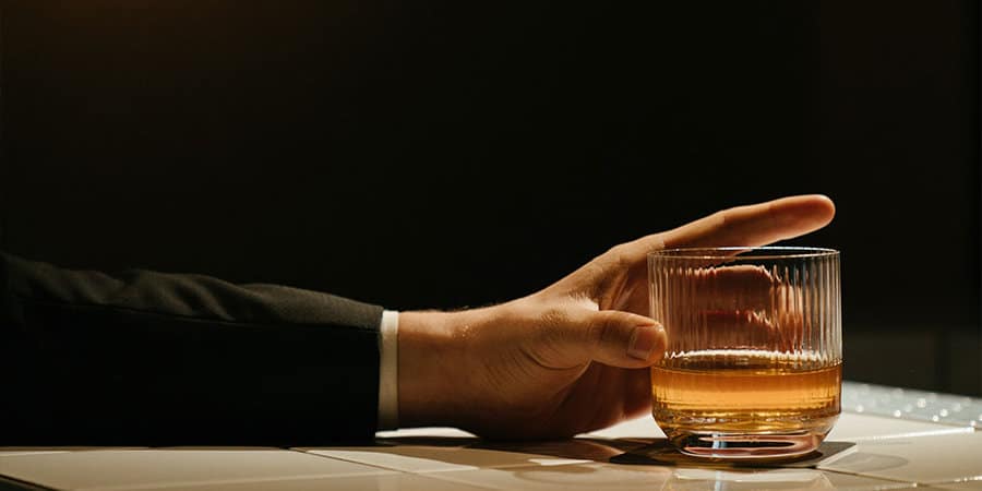 man gripping glass of whiskey