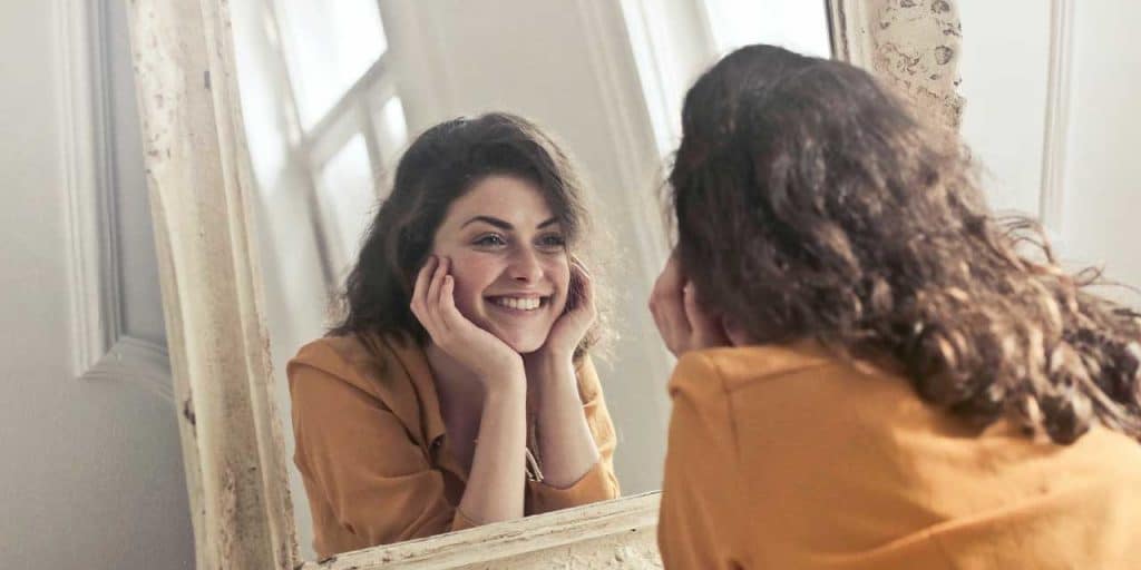woman looking in a mirror with high self-esteem