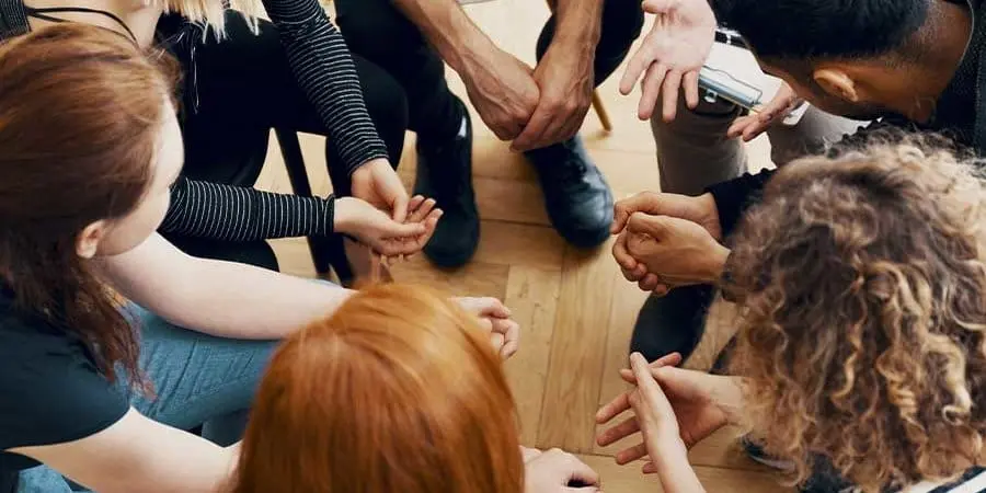 group of addiction treatment patients holding hands