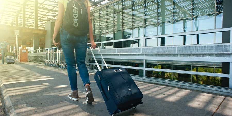 woman walking with suitcase through an airport terminal