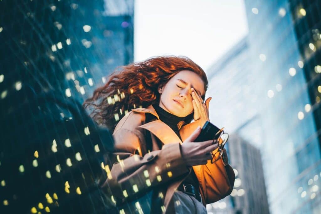 A stressed woman holding her phone and eyeglasses