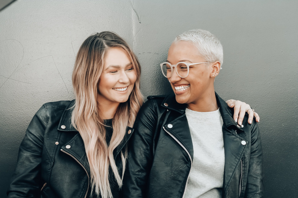 Two women look at each other while smiling.