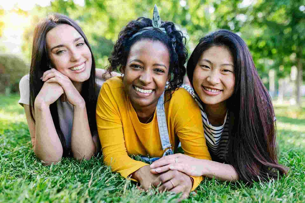 Group of young women smiling together on the grass.
